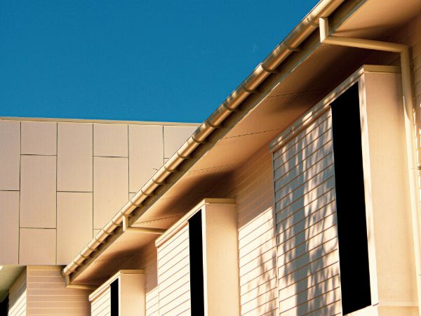 Modern commercial building featuring clean architectural lines, light beige siding, and dark window openings. Regular commercial power washing helps maintain this pristine appearance.